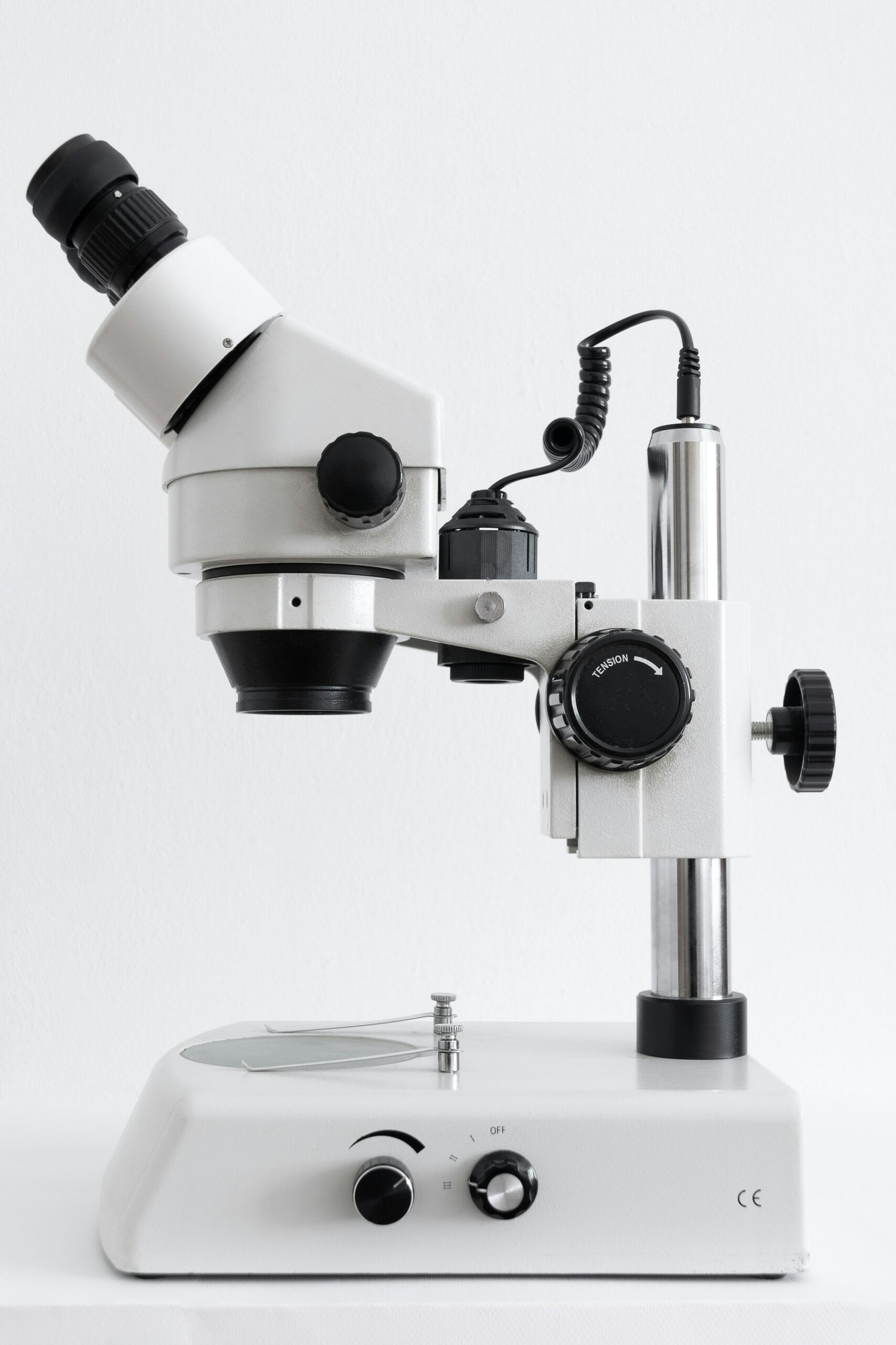 Image of a white microscope with black accessories on a white background